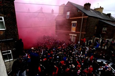 A flare burns as fans try to see the Manchester City team bus as it arrives ahead of the Champions League quarter final first leg soccer match between Liverpool and Manchester City at Anfield stadium in Liverpool, England, Wednesday, April 4, 2018. (AP Photo/Dave Thompson)