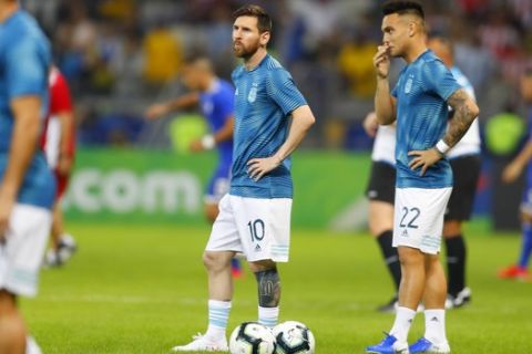 Argentina's Lionel Messi , center, and Lautaro Martinez stands at the field to warm up before a Copa America Group B soccer match against Paraguay at the Mineirao stadium in Belo Horizonte, Brazil, Wednesday, June 19, 2019. (AP Photo/Natacha Pisarenko)