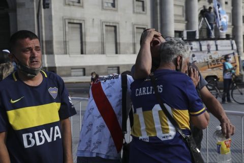 Soccer fans embrace as they wait to see Diego Maradona lying in state outside the presidential palace in Buenos Aires, Argentina, Thursday, Nov. 26, 2020. The Argentine soccer great who led his country to the 1986 World Cup title died Wednesday at the age of 60. (AP Photo/Rodrigo Abd)