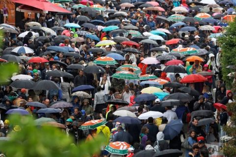 In this Saturday, June 3, 2017 photo, spectators take cover under umbrellas as third round matches were suspended because of rain showers at the French Open tennis tournament at the Roland Garros stadium, in Paris, France. (AP Photo/Petr David Josek)