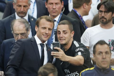 French President Emmanuel Macron, left, poses for a selfie with a soccer fan before the French Cup soccer final Paris Saint Germain against Les Herbiers at the Stade de France stadium in Saint-Denis, outside Paris, Tuesday, May 8, 2018. (AP Photo/Francois Mori)