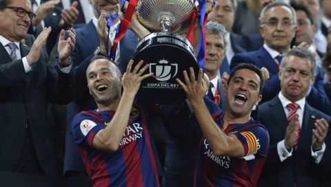 FILE - In this Saturday, May 30, 2015 file photo Barcelona's Andres Iniesta, left, and Xavi Hernandez lift the trophy after winning the final of the Copa del Rey soccer match between FC Barcelona and Athletic Bilbao at the Camp Nou stadium in Barcelona, Spain. (AP Photo/Manu Fernandez, File)