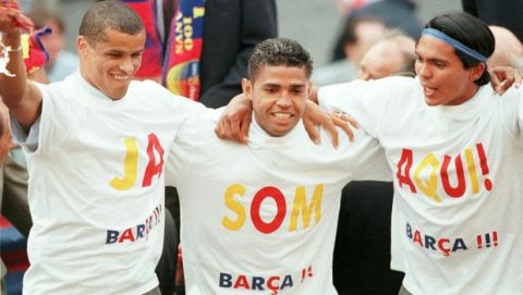 Barcelona's Brazilian players Rivaldo, left, Sonny Anderson, center, and Giovanni celebrate on an open double decker bus that paraded through Barcelona, Spain Monday May 24, 1999. Barcelona were proclaimed Spanish league champions last Saturday after beating Alaves. Their  T-Shirts, written in Catalan,  read " We are here" in reference to arriving in Barcelona's Plaza Saint Jaume, where they always celebrate title wins. (AP Photo/Paul White)