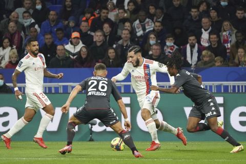 Lyon's Rayan Cherki, center, challenges for the ball with Monaco' players during the French League One soccer match between Lyon and Monaco at the Groupama stadium in Lyon, France, Saturday, Oct. 16, 2021. (AP Photo/Laurent Cipriani)