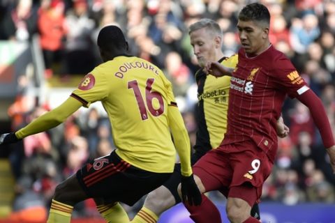 Liverpool's Roberto Firmino, right, challenges Watford's Abdoulaye Doucoure during the English Premier League soccer match between Liverpool and Watford at Anfield stadium in Liverpool, England, Saturday, Dec. 14, 2019. (AP Photo/Rui Vieira)