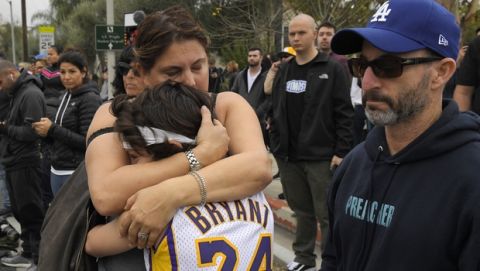 Elana Hirschman, left, hugs her son Bryan, 11, as her husband Craig stands by at the scene of a helicopter crash that killed former basketball player Kobe Bryant Sunday, Jan. 26, 2020, in Calabasas, Calif. (AP Photo/Mark J. Terrill)