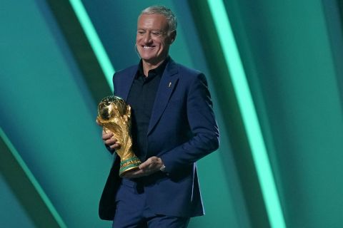 Reigning champions, France's head coach Didier Deschamps carries the World Cup trophy onstage during the 2022 soccer World Cup draw at the Doha Exhibition and Convention Center in Doha, Qatar, Friday, April 1, 2022. (AP Photo/Darko Bandic)