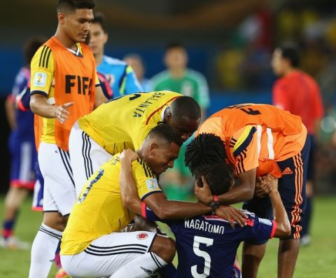 CUIABA, BRAZIL - JUNE 24:  Colombia players embrace Yuto Nagatomo of Japan after the 2014 FIFA World Cup Brazil Group C match between Japan and Colombia at Arena Pantanal on June 24, 2014 in Cuiaba, Brazil.  (Photo by Elsa/Getty Images)