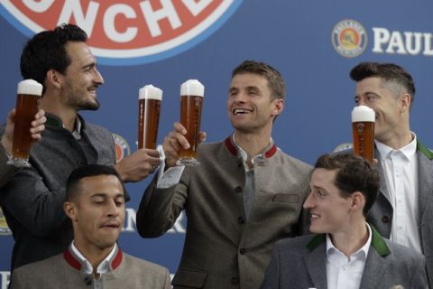 Bayern's Mats Hummels, left, and Robert Lewandowski, right, salut to team mate Thomas Mueller in traditional Bavarian clothes during a photo shooting of a beer brewing company in Munich, Germany, Wednesday, Sept. 13, 2017. Mueller celebrates his 28th birthday today. (AP Photo/Matthias Schrader)