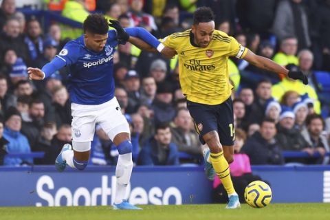 Everton's Mason Holgate, left, and Arsenal's Pierre-Emerick Aubameyang battle for the ball during the English Premier League soccer match between Everton and Arsenal at Goodison Park, Liverpool, England, Saturday, Dec. 21, 2019. (Anthony Devlin/PA via AP)