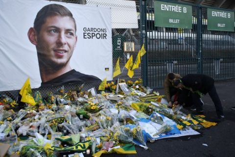 Nantes soccer team supporters lay flowers at a poster of Argentinian player Emiliano Sala and reading "Let's keep hope" outside La Beaujoire stadium before the French soccer League One match Nantes against Saint-Etienne, in Nantes, western France, Wednesday, Jan.30, 2019. Sala disappeared over the English Channel on Jan. 21, 2019 as it flew from France to Wales. Sala had just been signed by Premier League club Cardiff. (AP Photo/Thibault Camus)