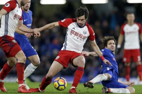 Chelsea's Cesc Fabregas, right, falls after a challenge from West Bromwich Albion's Claudio Yacob during the English Premier League soccer match between Chelsea and West Bromwich Albion at Stamford Bridge stadium in London, Monday, Feb. 12, 2018. (AP Photo/Alastair Grant)