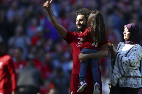 Liverpool's Mohamed Salah, accompanied by his wife Maggi greets supporters while holding his daughter Makka, age 5, at the end of the English Premier League soccer match between Liverpool and Wolverhampton Wanderers at the Anfield stadium in Liverpool, England, Sunday, May 12, 2019. Despite a 2-0 win over Wolverhampton Wanderers, Liverpool missed out on becoming English champion for the first time since 1990 because title rival Manchester City beat Brighton 4-1. (AP Photo/Dave Thompson)