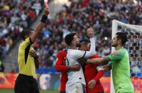 Argentina's Lionel Messi, center, and Chile's Gary Medel, center right, scuffle as referee Mario Diaz, from Paraguay, left, shows the red card to both of them during Copa America third-place soccer match at the Arena Corinthians in Sao Paulo, Brazil, Saturday, July 6, 2019. (AP Photo/Victor R. Caivano)