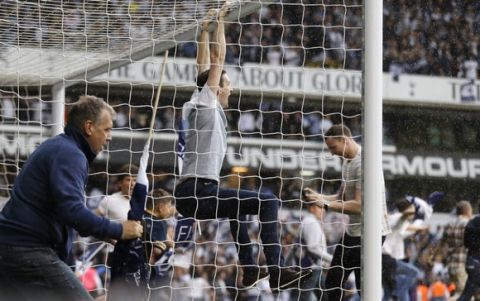 A fan swings on the goalpost as the pitch is invaded after the English Premier League soccer match between Tottenham Hotspur and Manchester United at White Hart Lane stadium in London, Sunday, May 14, 2017. It was the last Spurs match at the old stadium, a new stadium is being built on the site. (AP Photo/Frank Augstein)