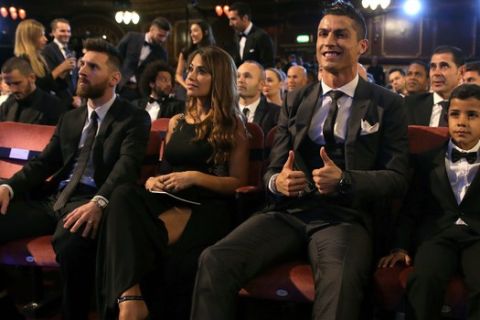 FILE - In this Monday, Oct. 23, 2017 file photo, Portuguese soccer player Christiano Ronaldo, second from right, and son Cristiano Ronaldo Jr., right, sit beside Argentinian soccer player Lionel Messi, left, and wife Antonella during the The Best FIFA 2017 Awards at the Palladium Theatre in London. Cristiano Ronaldo and Lionel Messi put up impressive numbers, in life and on the field, going into a fourth World Cup for each. So much has happened for football's standout stars since the 2014 tournament left both still lacking the game's most coveted prize. (AP Photo/Alastair Grant, File)