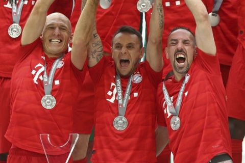 Front from left, Bayern's Arjen Robben, Rafinha, Franck Ribery and Manuel Neuer lift the trophy to celebrate Bayern's 7th straight Bundesliga title after the German Soccer Bundesliga match between FC Bayern Munich and Eintracht Frankfurt in Munich, Germany, Saturday, May 18, 2019. (AP Photo/Matthias Schrader)