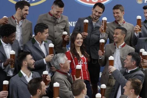 Bayern's players salut to Dafne, a young Bayern supporter, in traditional Bavarian clothes during a photo shooting of a beer brewing company in Munich, Germany, Wednesday, Sept. 13, 2017. Mueller celebrates his 28th birthday today. (AP Photo/Matthias Schrader)