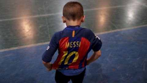 In this Nov. 11, 2016 photo, Benjamin Palandella puts on his Barcelona jersey adorned with Messi's number 10 after a training game at the youth soccer academy Club Social Parque in a working class neighborhood of Buenos Aires, Argentina. After the training game, Benjamin continued to kick the ball even after the other kids had gone home. (AP Photo/Natacha Pisarenko)
