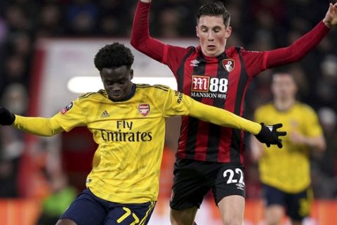 Arsenal's Bukayo Saka, left, and Bournemouth's Harry Wilson battle for the ball during the English FA Cup fourth round soccer match between AFC Bournemouth and Arsenal at Vitality Stadium, Bournemouth, England, Monday, Jan. 27, 2020. (John Walton/PA via AP)