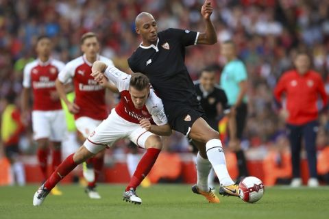 Arsenal's Aaron Ramsey, left, and Sevilla's Steven N'Zonzi battle for the ball during the Emirates Cup soccer match Arsenal against Sevilla FC at the Emirates Stadium, London, Sunday, July 30, 2017. (John Walton/PA via AP)