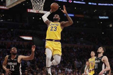 Los Angeles Lakers' LeBron James, center, goes up for a dunk as Washington Wizards' Jabari Parker, bottom left, and Tomas Satoransky look on during the first half of an NBA basketball game, Tuesday, March 26, 2019, in Los Angeles. (AP Photo/Jae C. Hong)