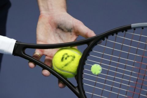 The tennis ball of french veteran Nicolas Mahut is marked with a sign during a training session in the French Tennis Federation center near the grounds of the French Open in Paris, Wednesday, May 13, 2020 under the watchful eye of a team doctor and courtside trainers. Professional tennis players resumed training in France after the end of lockdown amid the coronavirus pandemic. (AP Photo/Francois Mori)
