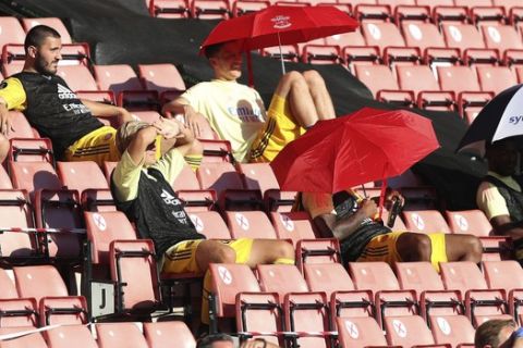 Arsenal's Mesut Ozil, center top, holds an umbrella as sits on the stands during the English Premier League soccer match between Southampton and Arsenal at St Mary's Stadium, in Southampton, England, Thursday, June 25, 2020. (Andrew Matthews/Pool via AP)