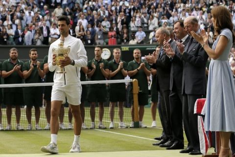 Serbia's Novak Djokovic walks with the trophy after defeating Switzerland's Roger Federer in the men's singles final match of the Wimbledon Tennis Championships in London, Sunday, July 14, 2019. (AP Photo/Tim Ireland)