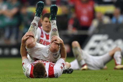 Cologne's players fall on the ground disappointed after the German Bundesliga soccer match between 1. FC Cologne and FC Schalke 04 in Cologne, Germany, Sunday, April 22, 2018. The match ended 2-2. (AP Photo/Martin Meissner)