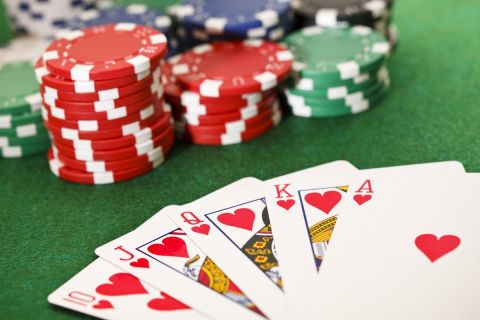 Poker cards showing the best poker hand -royal flush- and poker chips on a green card table. This is an exclusive image and it can only be found in iStockphoto.