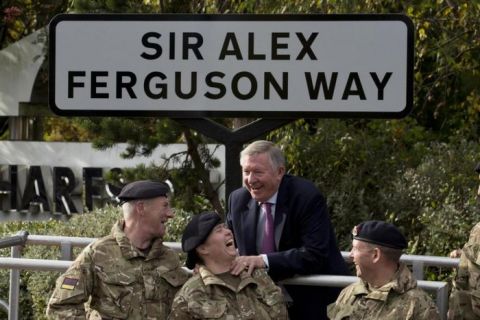 Manchester United's former manager Alex Ferguson, upper centre, jokes with soldiers as a street is named after him near Old Trafford Stadium, Manchester, England, Monday Oct. 14, 2013. Earlier in the day the side's manager for over 26 years was awarded the Honorary Freedom of the Borough of Trafford. (AP Photo/Jon Super)