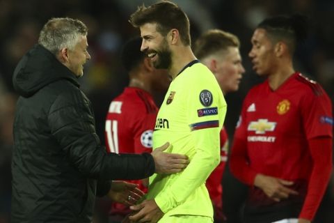 Manchester United coach Ole Gunnar Solskjaer, left, talks with Barcelona's Gerard Pique at the end of the Champions League quarterfinal, first leg, soccer match between Manchester United and FC Barcelona at Old Trafford stadium in Manchester, England, Wednesday, April 10, 2019. (AP Photo/Dave Thompson)