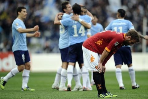 AS Roma's midfielder Daniele De Rossi (C) reacts as Lazio's  players celebrate their victory 2-1 after an Italian Serie A football match in Rome's Olympic Stadium on March 4, 2012.  AFP PHOTO / Filippo MONTEFORTE (Photo credit should read FILIPPO MONTEFORTE/AFP/Getty Images)