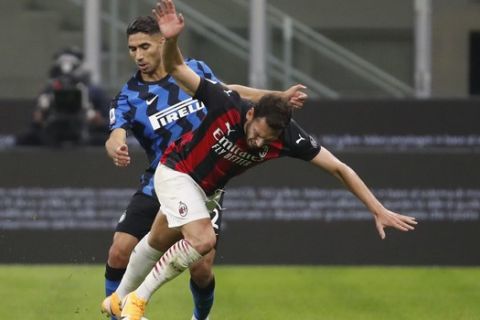 AC Milan's Hakan Calhanoglu, right, and Inter Milan's Achraf Hakimi vie for the ball during the Serie A soccer match between Inter Milan and AC Milan at the San Siro Stadium, in Milan, Italy, Saturday, Oct. 17, 2020. (AP Photo/Antonio Calanni)