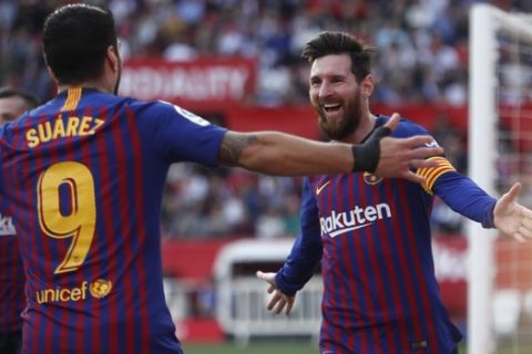 Barcelona forward Lionel Messi with his teammate Luis Suarez celebrate after scoring his side's third goal during La Liga soccer match between Sevilla and Barcelona at the Ramon Sanchez Pizjuan stadium in Seville, Spain. Saturday, February 23, 2019. (AP Photo/Miguel Morenatti)