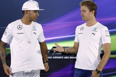 In this Thursday, Nov. 20, 2014 photo, Mercedes driver Lewis Hamilton of Britain, left, looks at his teammate Nico Rosberg of Germany before shaking hand prior to a news conference at the Yas Marina racetrack in Abu Dhabi, United Arab Emirates. Rosberg's announcement on Friday, Dec. 2, 2016 that he was retiring at the age of 31, five days after earning his first Formula One world championship, shocked the world of motor racing. (AP Photo/Luca Bruno)