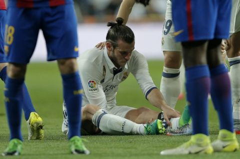 Real Madrid's Gareth Bale holds his leg after getting injured during a Spanish La Liga soccer match between Real Madrid and Barcelona, dubbed 'el clasico', at the Santiago Bernabeu stadium in Madrid, Spain, Sunday, April 23, 2017. (AP Photo/Daniel Ochoa de Olza)