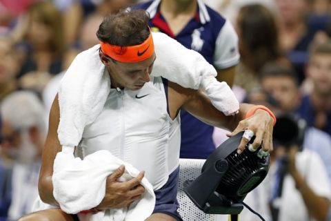 Rafael Nadal, of Spain, wears a cooling vest and holds a fan during a changeover in his quarterfinal against Dominic Thiem, of Austria, at the U.S. Open tennis tournament Tuesday, Sept. 4, 2018, in New York. (AP Photo/Adam Hunger)