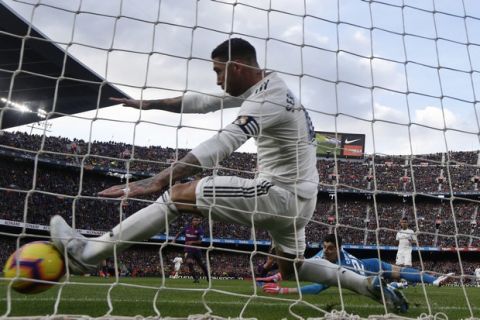 Real defender Sergio Ramos tries to block the ball as Barcelona forward Philippe Coutinho scores his side's opening goal during the Spanish La Liga soccer match between FC Barcelona and Real Madrid at the Camp Nou stadium in Barcelona, Spain, Sunday, Oct. 28, 2018. (AP Photo/Manu Fernandez)