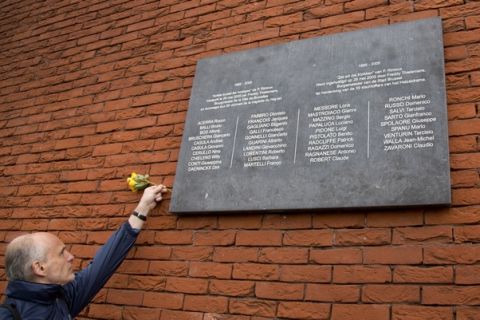 A man leaves a flower at a memorial plaque during a commemoration at the King Boudouin (formerly the Heysel) Stadium in Brussels on Friday, May 29, 2015. Friday marks 30 years since 39 victims lost their lives during a European Cup football match between Liverpool and Juventus due to a surge of rival supporters resulting in a collapsed wall. (AP Photo/Virginia Mayo)