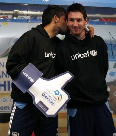 Argentina's Sergio Aguero (L) kisses teammate and UNICEF ambassador Lionel Messi during a UNICEF event at the squad's camp ahead of the Copa America tournament in Buenos Aires, June 24, 2011. REUTERS/Marcos Brindicci (ARGENTINA - Tags: SPORT SOCCER)