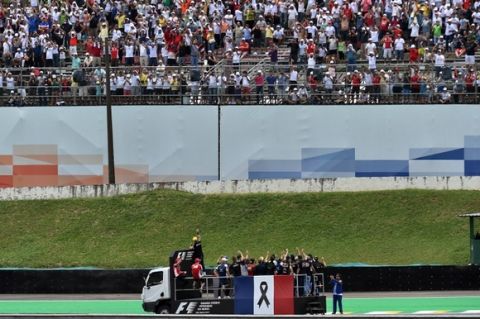 TOPSHOTS
Formula One drivers parade atop a truck with a French flag decorated with a black ribbon in homage to the victims of the terrorist attacks in Paris, before the start of the Brazilian Grand Prix, at the Interlagos racetrack in Sao Paulo, on November 15, 2015.  AFP PHOTO / NELSON ALMEIDA