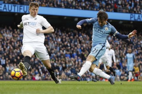 Manchester City's David Silva, right, has a shot on goal during the English Premier League soccer match between Manchester City and Swansea City at the Etihad Stadium, Manchester, England, Sunday, Feb. 5, 2017. (Martin Rickett/PA via AP)