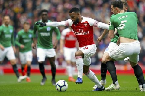 Arsenal's Alexandre Lacazette, left, and Brighton & Hove Albion's Lewis Dunk battle for the ball during the English Premier League soccer match at the Emirates Stadium, London, Sunday May 5, 2019. (John Walton/PA via AP)