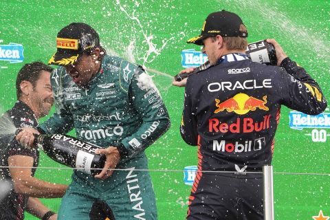 Red Bull driver Max Verstappen of the Netherlands,center, sprays champagne on the podium with second place Aston Martin driver Fernando Alonso of Spain after winning the Formula One Dutch Grand Prix at the Zandvoort racetrack, in Zandvoort, Netherlands, Sunday, Aug. 27, 2023.(AP Photo/Peter Dejong)