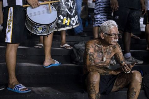 TO GO WITH AFP STORY by Javier Tovar
Brazilian football club Botafogo fan Delneri Martins Viana, a 69-year-old retired soldier, applauds at the team during a match at Sao Genario stadium in Rio de Janeiro, Brazil, on January 21, 2014. Delneri has 83 tattoos on his body dedicated to Botafogo and describes himself as the club's biggest fan.   AFP PHOTO / YASUYOSHI CHIBA