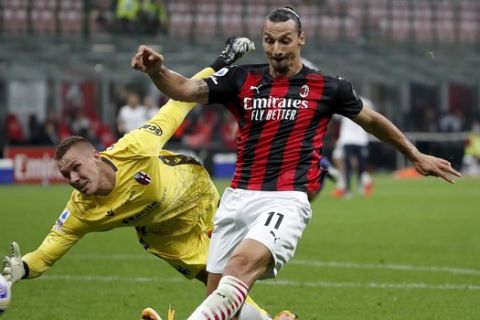 AC Milan's Zlatan Ibrahimovic, right, kick the ball as Bologna's goalkeeper Lukasz Skorupski try to stop the ball during the Serie A soccer match between AC Milan and Bologna at the San Siro stadium, in Milan, Italy, Monday, Sept. 21, 2020. (AP Photo/Antonio Calanni)
