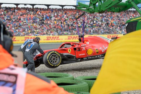 Track marshals collect debris and car of Ferrari driver Sebastian Vettel of Germany after a crash during the German Formula One Grand Prix at the Hockenheimring racetrack in Hockenheim, Germany, Sunday, July 22, 2018. (AP Photo/Jens Meyer)