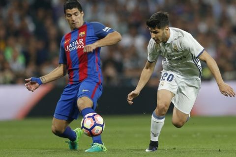 Real Madrid's Marco Asensio, right, challenges for the ball with Barcelona's Luis Suarez during a Spanish La Liga soccer match between Real Madrid and Barcelona, dubbed 'el clasico', at the Santiago Bernabeu stadium in Madrid, Spain, Sunday, April 23, 2017. (AP Photo/Francisco Seco)